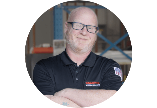 RSC Operator Training Specialist James West smiling at the camera in RSC black polo with warehouse in background.