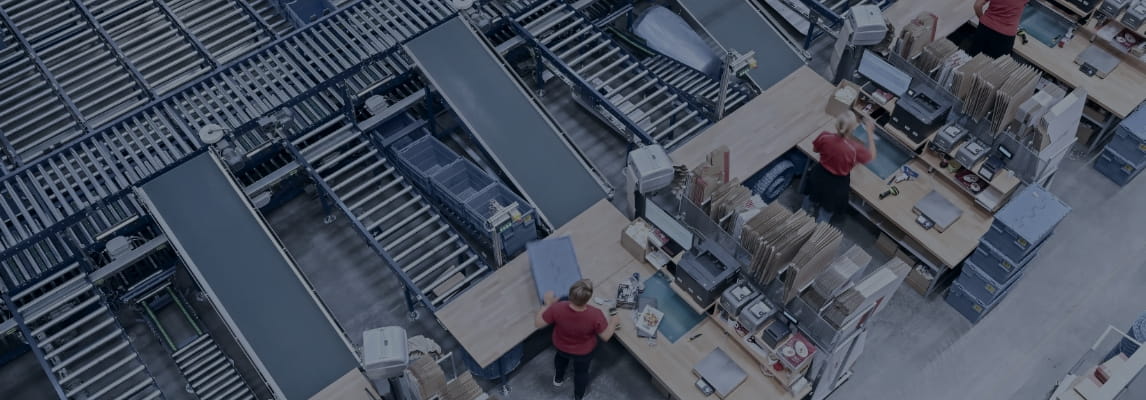 Warehouse workers packing orders at stations integrated with a conveyor system.