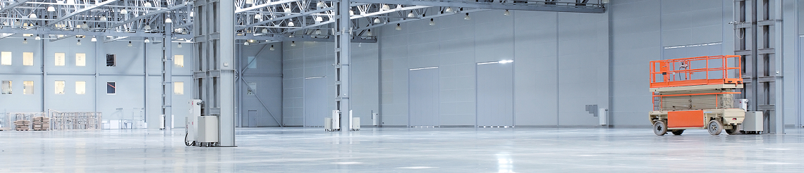Orange scissor lift for elevated warehouse maintenance and installation tasks.