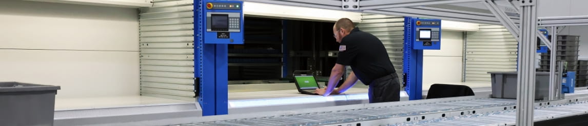 RSC technician adjusting automated storage and retrieval systems using a diagnostic laptop.