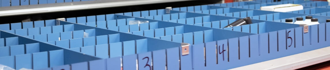 Close up of a blue AS/RS tray with forklift equipment parts inside its slots.