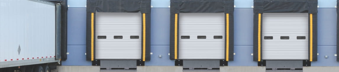 Exterior dock area of warehouse with a trailer pulled into one dock.