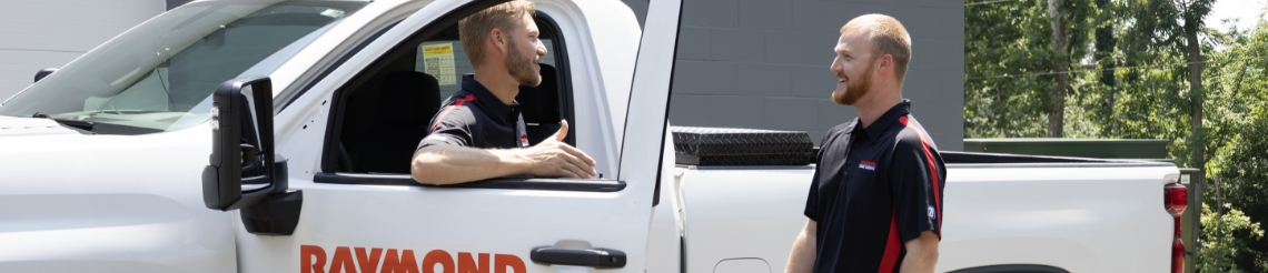 Two RSC employees talking next to an RSC truck outside a building.