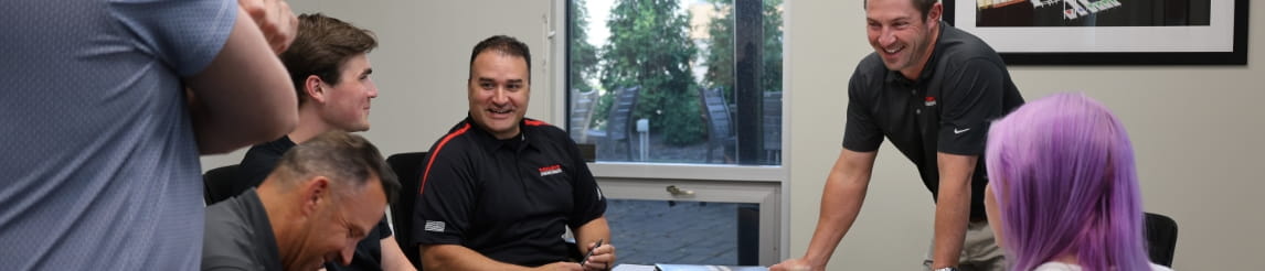 RSC engineered solutions team gather in conference room around a blueprint on the table.