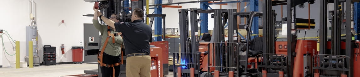 RSC trainer demonstrating safety tether to a forklift operator during a training session in a warehouse. 