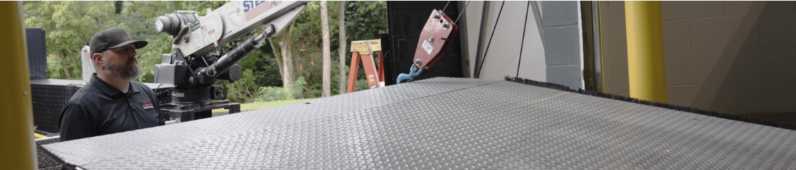RSC Dock & Door technician using a truck crane to strutting a dock leveler during maintenance visit.