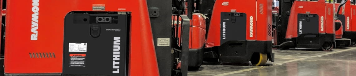 Several standing Raymond counterbalanced forklifts using lithium-ion batteries in a warehouse.