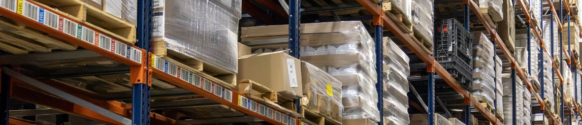 Warehouse racking aisle full of wrapped pallets.