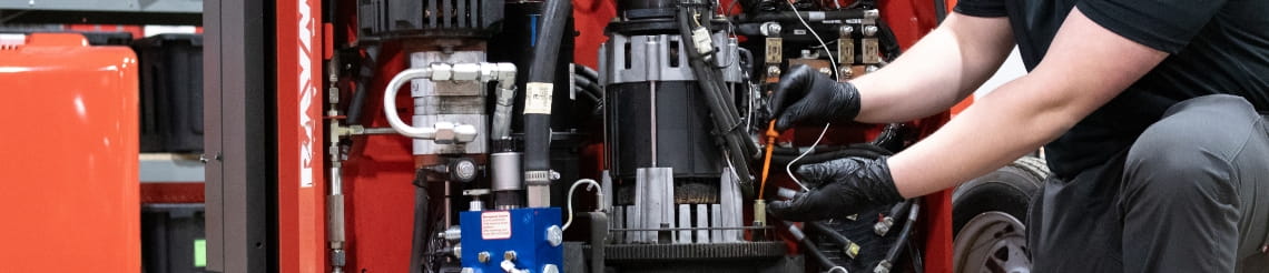 RSC technician gloved hands checking the oil in an open forklift. The engine is exposed to work on.