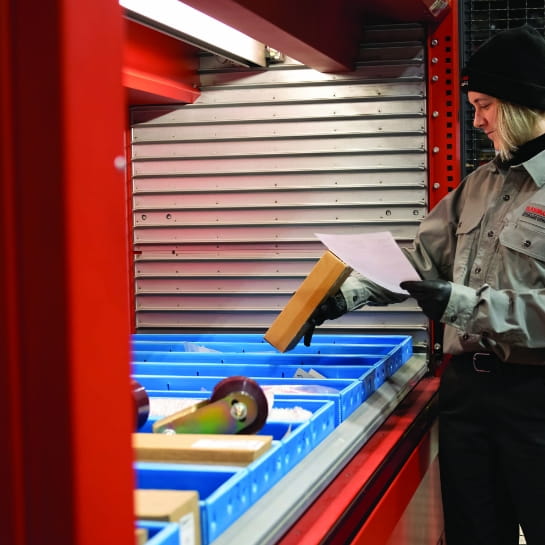 RSCI worker pulling parts while looking a paper parts order from AS/RS sytem.