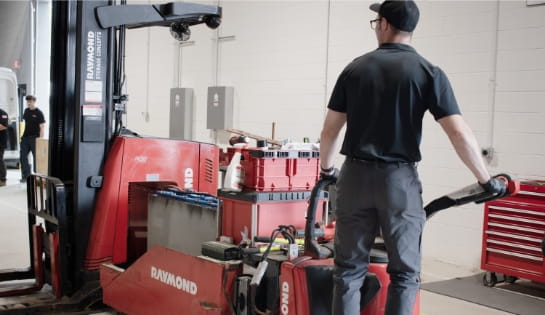 RSC technician extracting an old battery from a Raymond forklift.