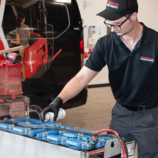 RSC technician performing lead-acid battery maintenance beside a branded service van.