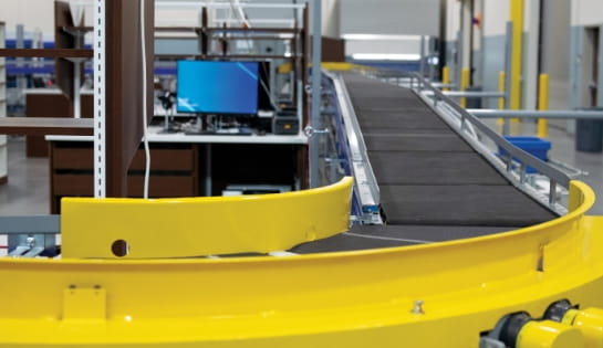 Belt conveyor curving in front of the viewer with computer control station.