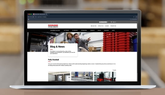 Laptop sitting on a tabletop with warehouse in background. The RSC blog webpage is on the laptop screen.