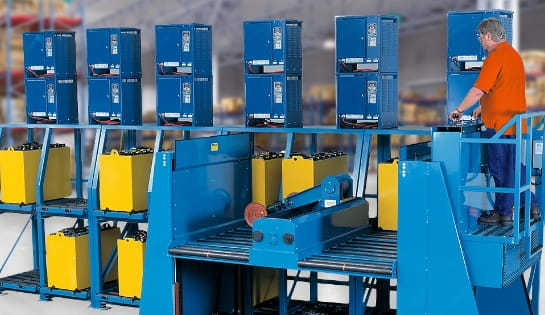 Man working a semi-automated forklift battery handling system in a warehouse. Extractor placing spent batteries onto shelves to re-charger on battery chargers.