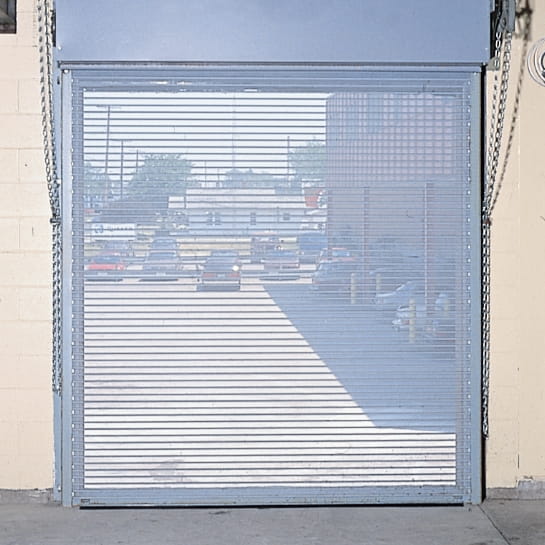 Bug barrier rolling door in a wall. You can see through the screen door into the parking lot.