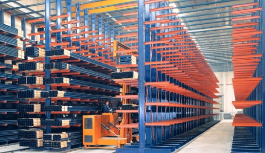 Multiple rows of blue and orange cantilever racking in a warehouse.