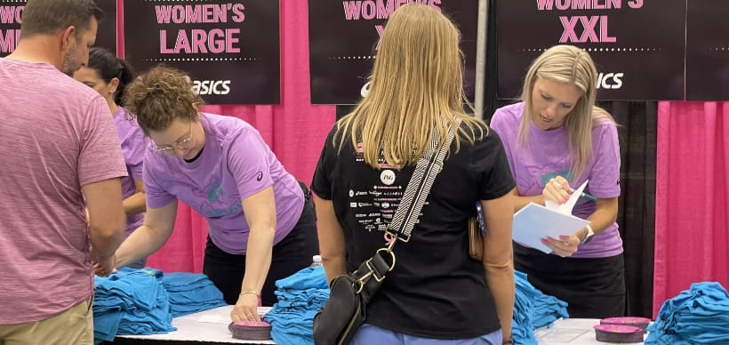 Two RSC employees volunteering at Cincinnati's Flying Pig Marathon. They are handing our t-shirts to marathon runners.