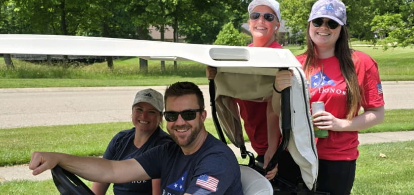 Members of the RSC Community Outreach Committee driving a golf cart at the Folds of Honor shootout event.