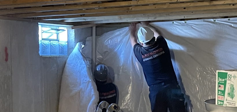 Two RSC employees hanging a vapor barrier in a basement during a Habitat for Humanity build event.