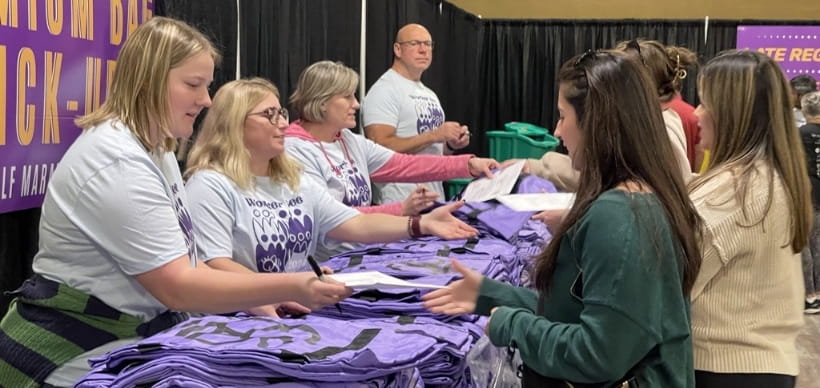 Team of RSC employees volunteer handing out shirts to Queen Bee Marathon runners.