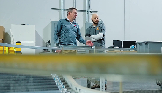 RSC engineer discussing a new conveyor system with a warehouse manager from Container & Packaging.