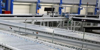 Conveyor running across and back in front of picking stations and vertical lift modules.