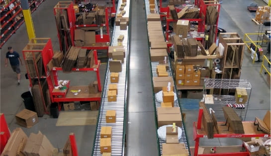 An accumulated conveyor system in place at Specialized Bicycles distribution. Includes parallel running conveyors with pickers on either side packing orders and placing completed boxes on conveyor.