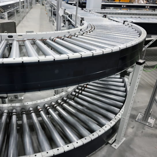 A stacked conveyor belt system curving around to connect to another conveyor line.