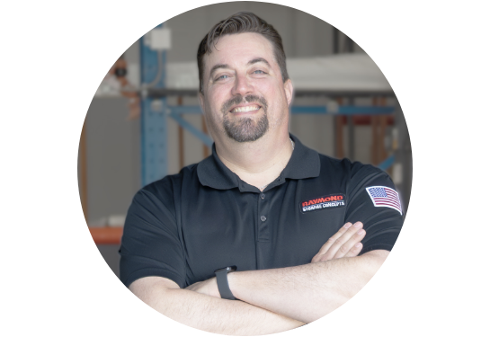 RSC Operator Training Specialist David Haushalter smiling at the camera in RSC black polo with warehouse in background.