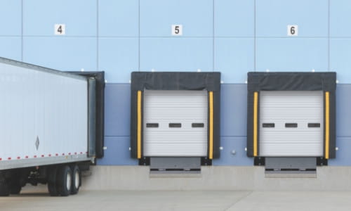 Exterior dock area of warehouse with a trailer pulled into one dock.