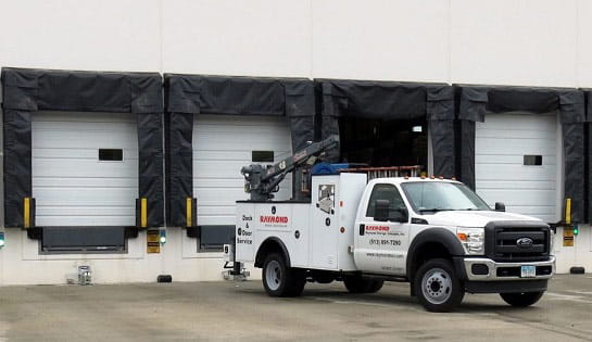 Raymond Storage Concepts Dock & Door service truck parked in front of warehouse dock area.