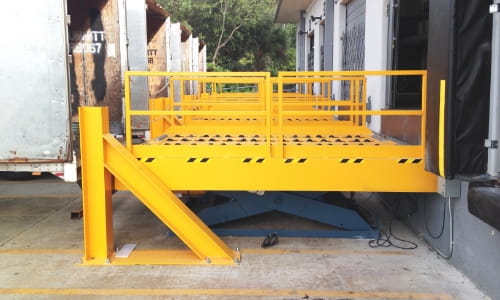 Yellow dock lift bridging a truck trailer to dock door.