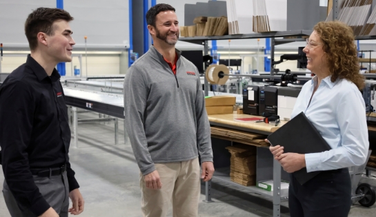 Two male RSC engineers speak with a female customer in a warehouse picking area.