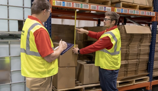 RSC engineer is measuring a pallet and racking spacing while another RSC engineer writes the measurements down.