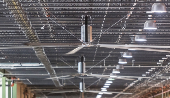 A row of HVLS industrial fans on a warehouse ceiling.