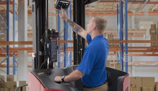 Forklift driver clicking an iWAREHOUSE monitor screen on his Raymond forklift.
