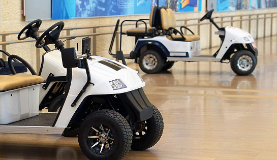 Two parked white golf carts in a hallway