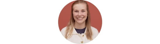 Hannah Holliday, RSC recruiter, smiling at the camera in white sweater with red wall background.