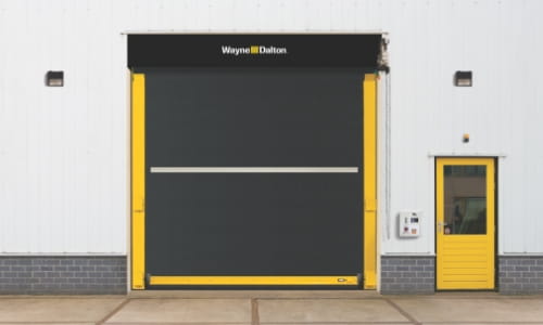 Black rubber high speed door in interior of warehouse next to yellow person door