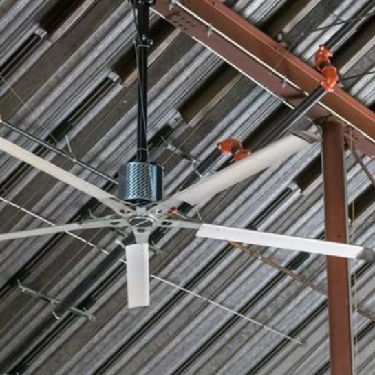A HVLS fan hanging from a warehouse ceiling.