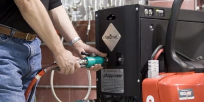 Set of hands hooking up a hose to a hydrogen fuel cell to re-fuel it.