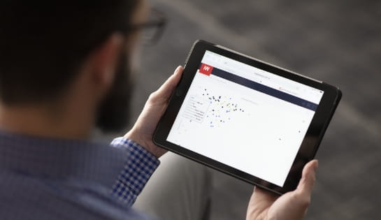 Man looking at a tablet screen. The screen is showing iWAREHOUSE's iBATTERY dashboard on battery energy usage.