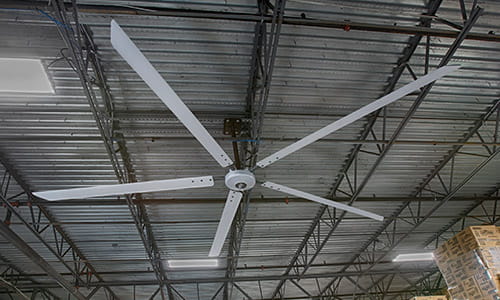 Large industrial fan on warehouse ceiling.