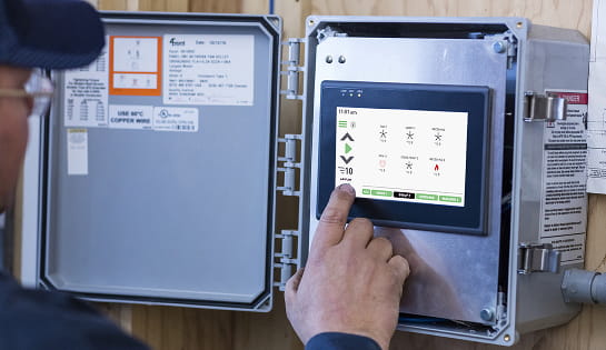 A person clicking on an industrial fan control panel.