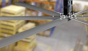 Close up of a warehouse industrial fan with pallets in the background.