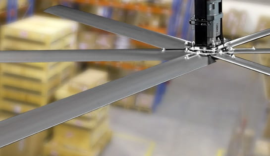 Close up of a warehouse industrial fan with pallets in the background.