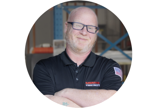 RSC Operator Training Specialist James West smiling at the camera in RSC black polo with warehouse in background.