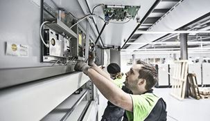 Technician working on a Kardex Remstar machine with the top hatch open.