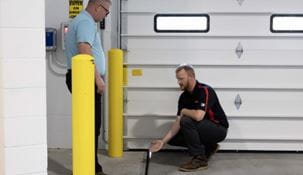 Dock & Door specialist pointing out a crack next to the dock leveler to a customer.